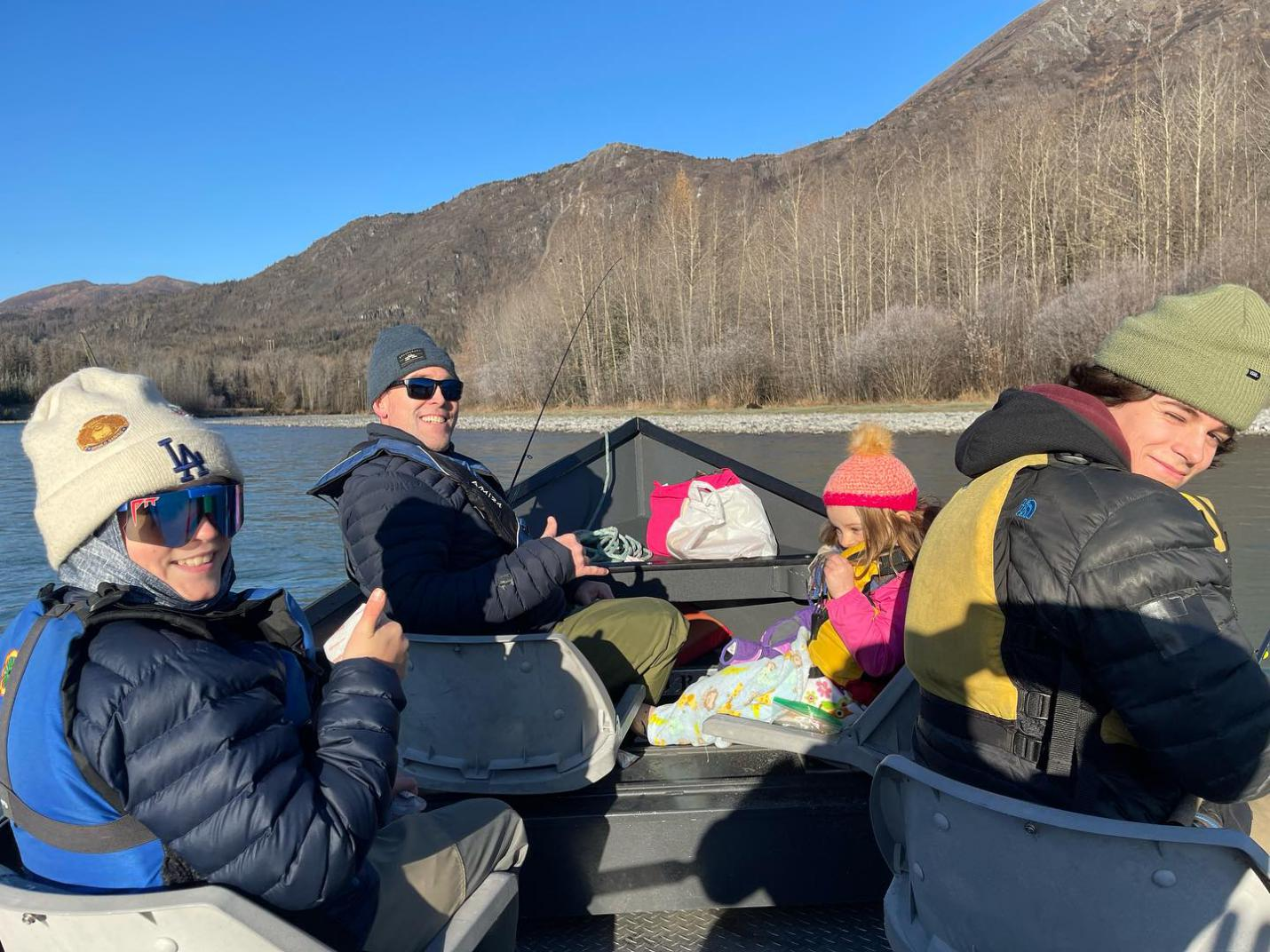 A family fishing together on a boat on the Kenai River, experiencing a guided fishing trip.