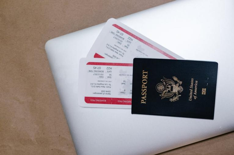 A close-up of a passport, tickets, and laptop, representing the essential travel preparations when renewing your passport.